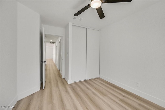 unfurnished bedroom featuring ceiling fan, light wood-type flooring, and a closet