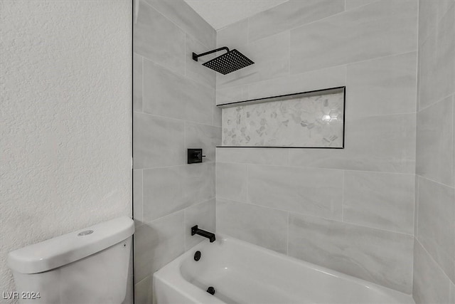 bathroom featuring tiled shower / bath combo and toilet