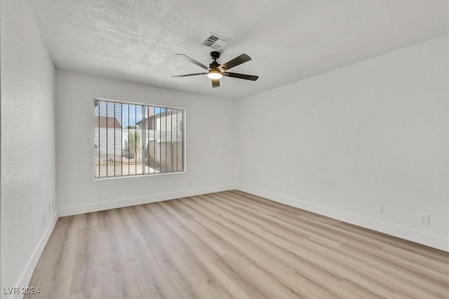 spare room featuring ceiling fan, light hardwood / wood-style flooring, and a textured ceiling