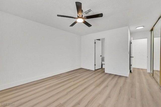 unfurnished bedroom featuring ceiling fan, light hardwood / wood-style floors, a closet, and ensuite bath