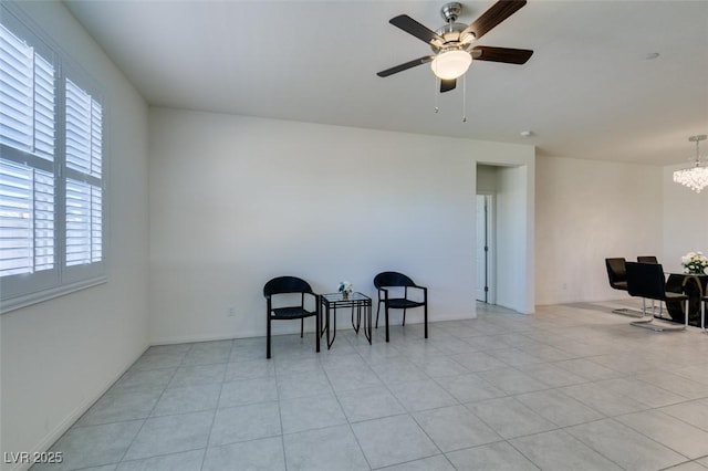 living area featuring light tile patterned floors, ceiling fan with notable chandelier, and plenty of natural light