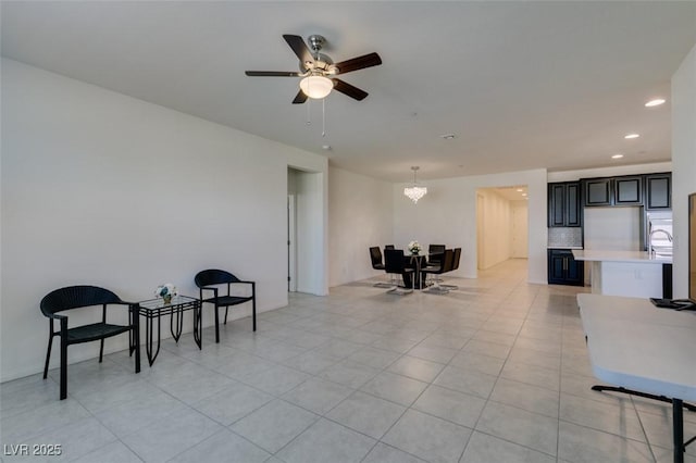 living area with light tile patterned floors and ceiling fan with notable chandelier