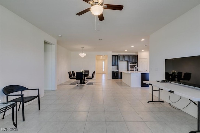 living room with ceiling fan with notable chandelier, sink, and light tile patterned floors