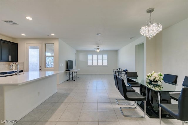 tiled dining room featuring ceiling fan with notable chandelier and sink