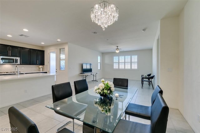 dining area featuring light tile patterned floors, ceiling fan with notable chandelier, and sink