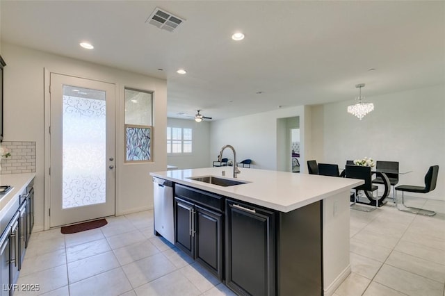 kitchen featuring sink, stainless steel dishwasher, an island with sink, decorative light fixtures, and ceiling fan with notable chandelier