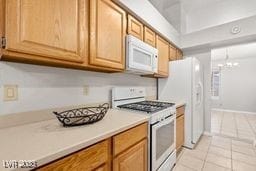 kitchen featuring light tile patterned flooring, a chandelier, and white appliances