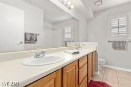 bathroom with toilet, vanity, tile patterned floors, and walk in shower