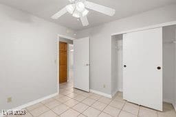 unfurnished bedroom with light tile patterned flooring, a closet, and ceiling fan