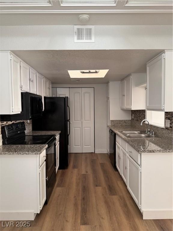 kitchen featuring sink, white cabinetry, dark wood-type flooring, and black appliances