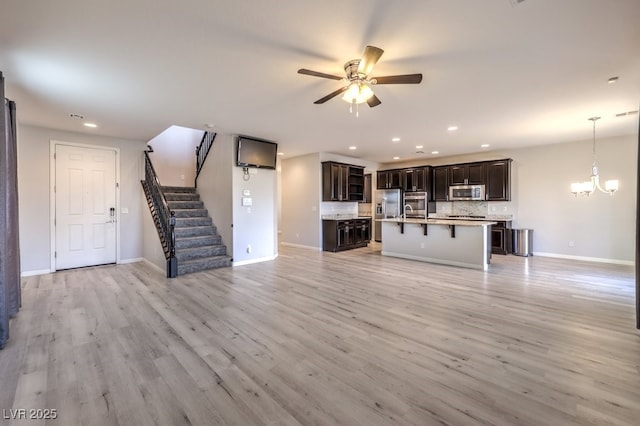 unfurnished living room featuring light hardwood / wood-style flooring and ceiling fan with notable chandelier