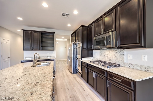 kitchen with sink, dark brown cabinets, light hardwood / wood-style floors, light stone counters, and stainless steel appliances