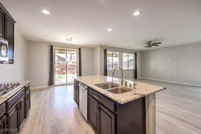 kitchen with a wealth of natural light, sink, stainless steel appliances, and a center island with sink