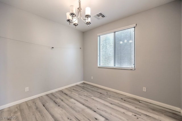 unfurnished room with a chandelier and light wood-type flooring