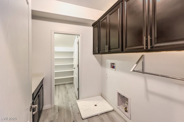 laundry area with hookup for a washing machine, light hardwood / wood-style flooring, and cabinets