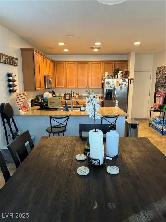 kitchen featuring sink, kitchen peninsula, stainless steel appliances, and a breakfast bar area