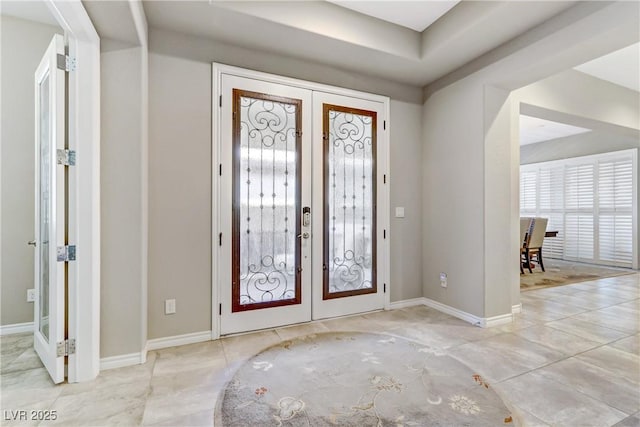 foyer featuring a tray ceiling and french doors