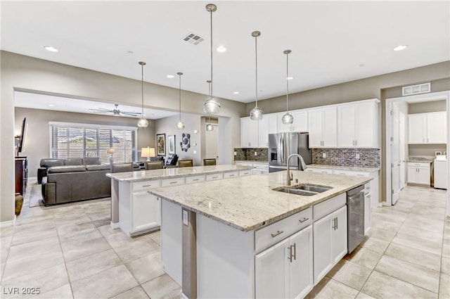 kitchen featuring ceiling fan, sink, hanging light fixtures, stainless steel appliances, and a center island with sink