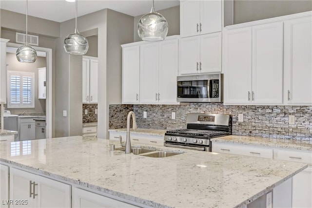 kitchen featuring pendant lighting, white cabinets, stainless steel appliances, and sink