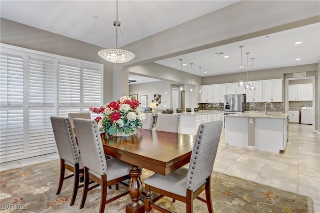 tiled dining room featuring a chandelier, washer / clothes dryer, and sink