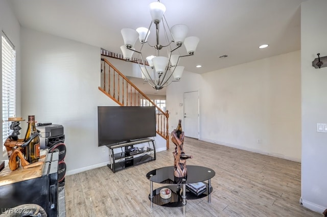 living room with light hardwood / wood-style floors and a notable chandelier