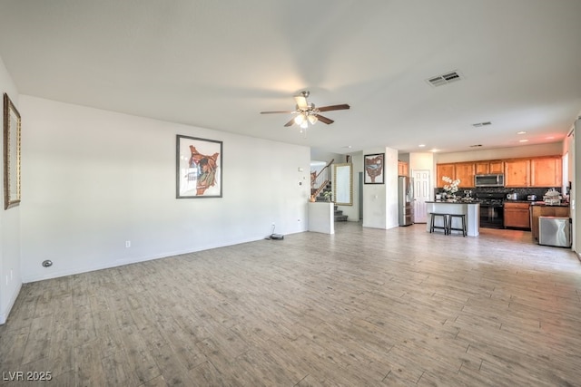 unfurnished living room featuring ceiling fan and light wood-type flooring