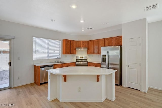 kitchen with visible vents, light wood-style flooring, under cabinet range hood, a sink, and appliances with stainless steel finishes