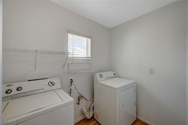 washroom featuring laundry area, baseboards, and separate washer and dryer