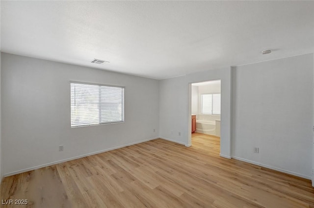 spare room featuring light wood-type flooring, baseboards, and visible vents