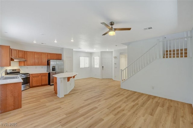 kitchen featuring visible vents, light wood finished floors, stainless steel appliances, under cabinet range hood, and open floor plan