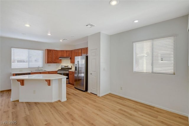 kitchen with visible vents, a sink, light countertops, appliances with stainless steel finishes, and a kitchen breakfast bar