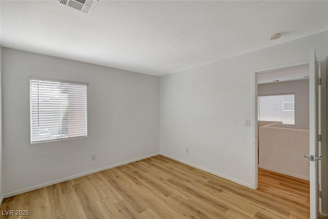 unfurnished room featuring visible vents, plenty of natural light, baseboards, and wood finished floors