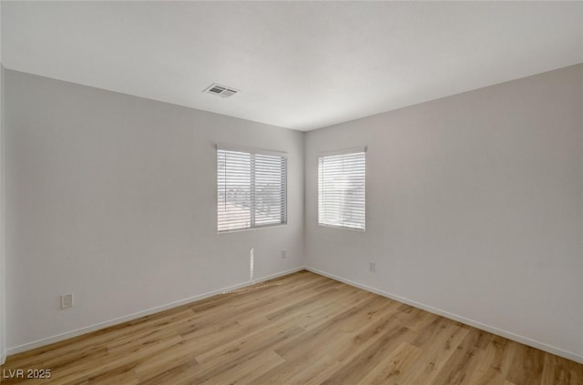 spare room with light wood-type flooring, baseboards, and visible vents