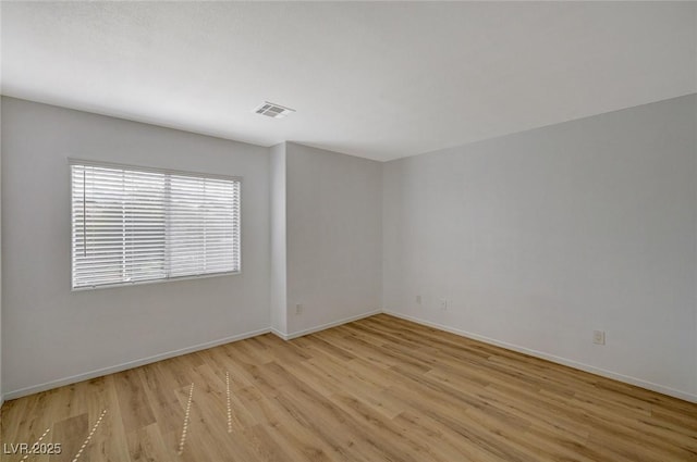 spare room featuring visible vents, light wood-type flooring, and baseboards