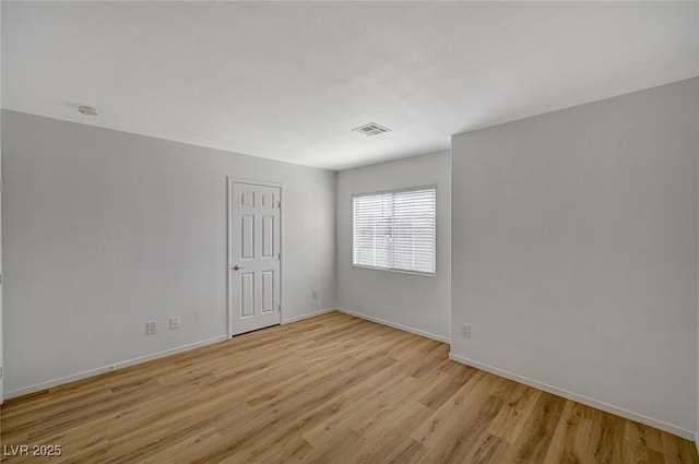 unfurnished room with visible vents, light wood-style flooring, and baseboards