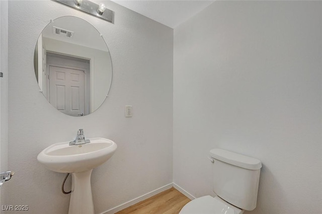 bathroom with visible vents, baseboards, toilet, and wood finished floors