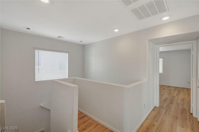 hallway with recessed lighting, visible vents, an upstairs landing, and light wood-style floors