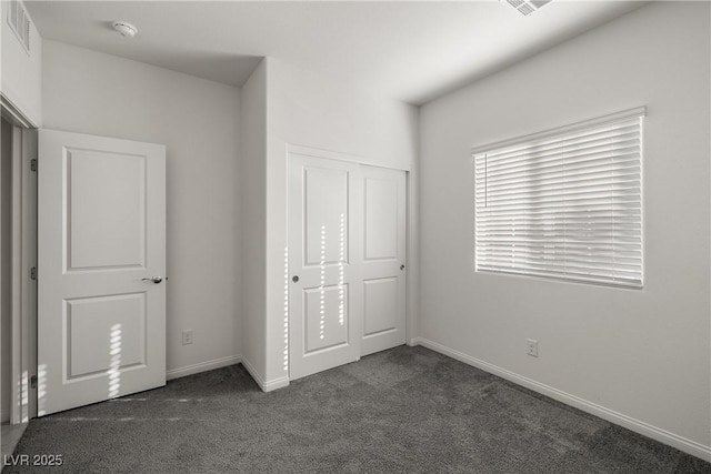 unfurnished bedroom with dark carpet and a closet