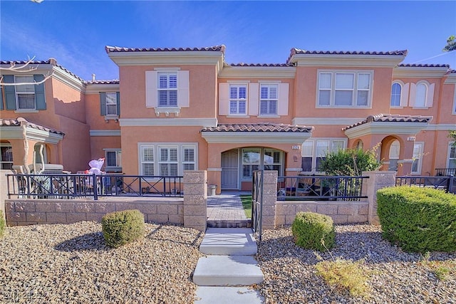 view of front facade with a fenced front yard, stucco siding, and a tile roof