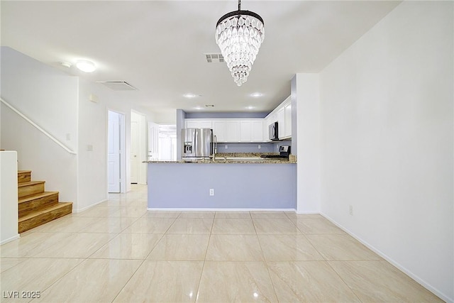 kitchen with an inviting chandelier, stainless steel appliances, stone counters, white cabinetry, and visible vents