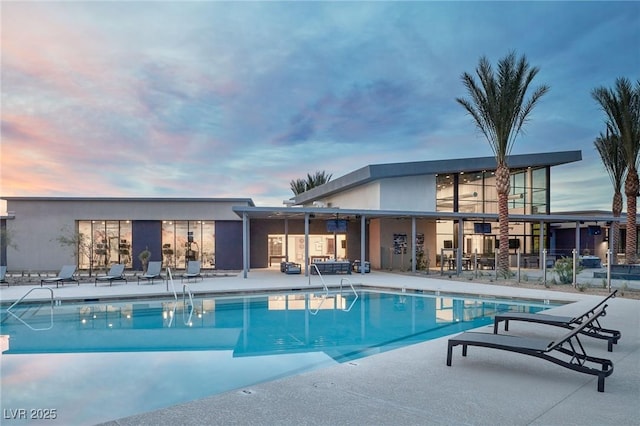 pool at dusk featuring a patio area