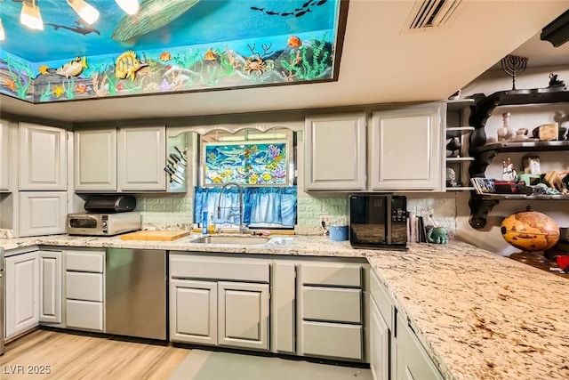 kitchen with white cabinetry, sink, light stone counters, and light wood-type flooring