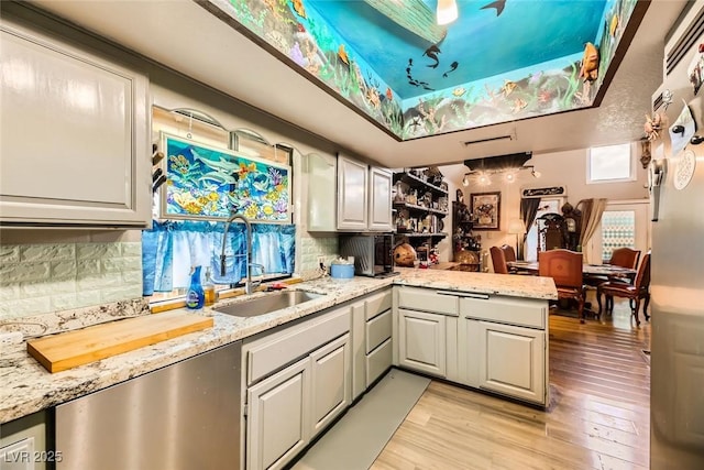 kitchen featuring light stone countertops, backsplash, kitchen peninsula, light hardwood / wood-style floors, and white cabinets