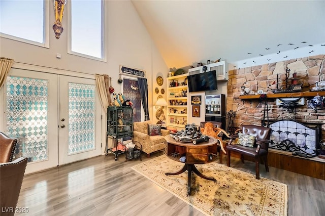 living room featuring wood-type flooring, high vaulted ceiling, and french doors