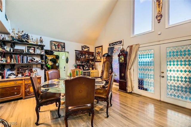 dining room with light hardwood / wood-style floors, high vaulted ceiling, and french doors