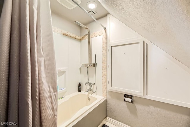 bathroom featuring shower / bathtub combination with curtain and a textured ceiling