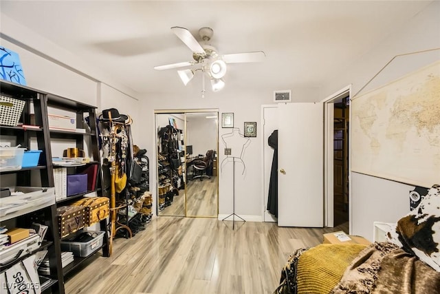 workout room with ceiling fan and light hardwood / wood-style flooring