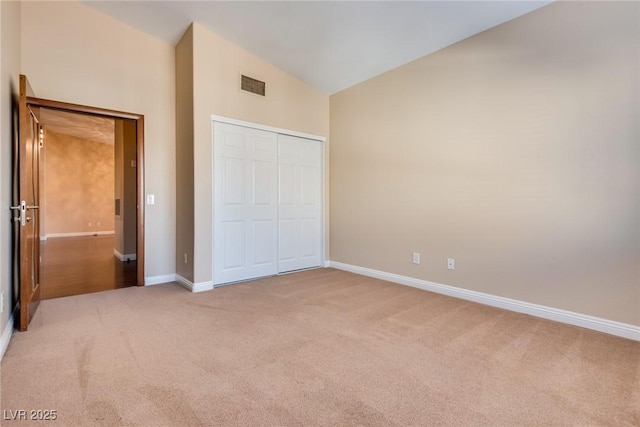 unfurnished bedroom featuring carpet flooring, lofted ceiling, and a closet