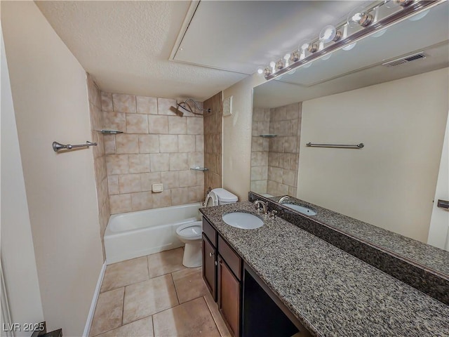 full bathroom featuring tiled shower / bath combo, tile patterned floors, a textured ceiling, toilet, and vanity