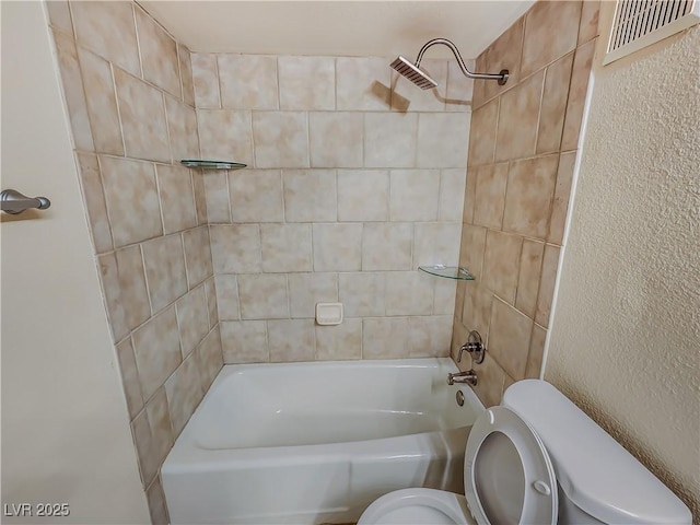 bathroom featuring tiled shower / bath combo and toilet